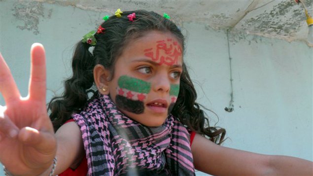 Une enfant syrienne montre un signe de victoire lorsqu'elle aperçoit de l'aide humanitaire arriver dans la ville de Houla, le 7 juin 2012.