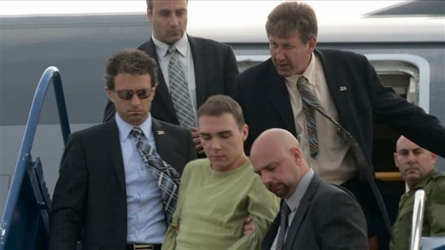 Luka Rocco Magnotta à sa sortie de l'avion, escorté par de nombreux corps policiers.