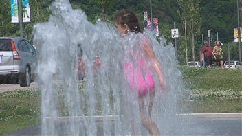 Une fillette s'amuse dans un jeu d'eau.