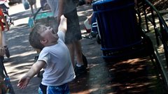 Un bambin se laisse asperger d'eau pour se rafraîchir.