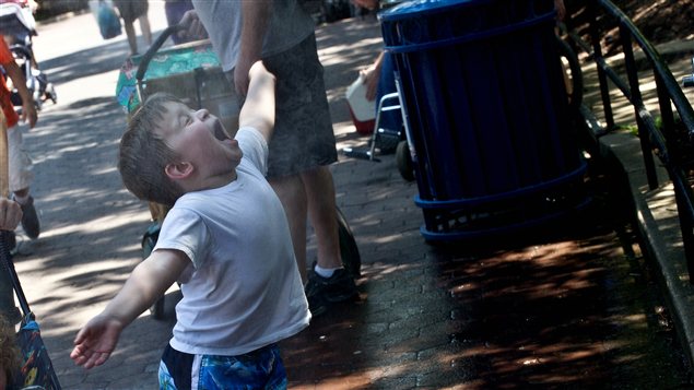 Un bambin se laisse asperger d'eau pour se rafraîchir.