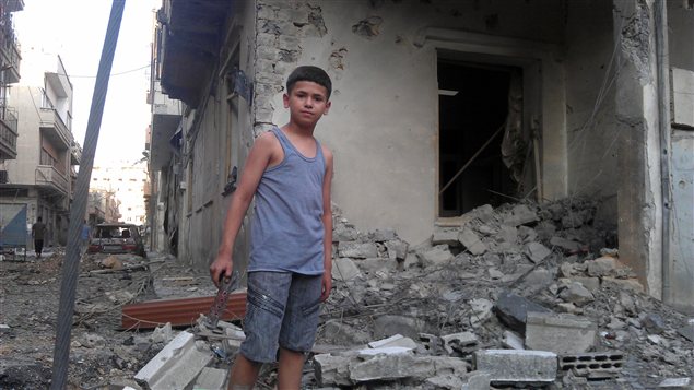 Un jeune garçon devant les ruines de sa maison dans un quartier de Homs, le 11 juillet 2012