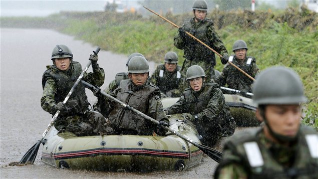 Militaires des forces d'autodéfense à la recherche de victimes des inondations
