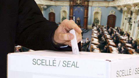 Un �lecteur d�pose un bulletin dans l'urne de votation | � Presse Canadienne