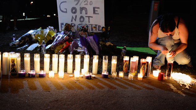 Une femme allume une chandelle pour honorer la mémoire des victimes de la tuerie du cinéma d'Aurora, au Colorado