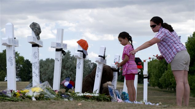 Une femme et une petite fille déposent des fleurs aux pieds de croix blanches érigées en l'honneur des victimes de la tuerie d'Aurora.