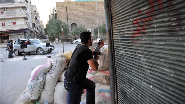 Un rebelle syrien en position alors que les hélicoptères de l'armée survolent le ciel de la ville d'Alep, en Syrie.