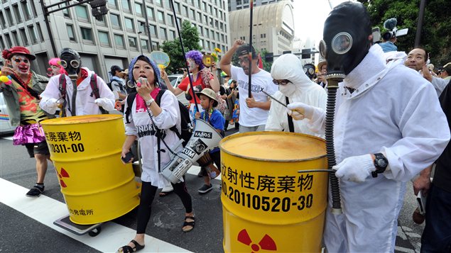 Des militants en combinaison blanche et munis de masques à gaz défilent à Tokyo pour dénoncer le nucléaire et la remise en service de deux réacteurs de la centrale d'Ohi.