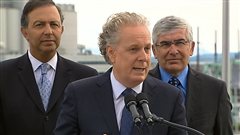 Entouré des ministres Sam Hamad et Clément Gignac, Jean Charest a nié toute intervention dans la fin de la filature d'Eddy Brandone.