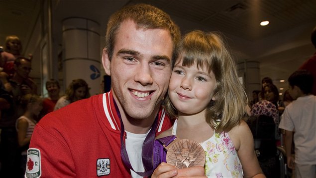 Le judoka Antoine Valois-Fortier montre sa médaille de bronze au côté de sa petite soeur Alice à l'aéroport international Pierre-Elliot-Trudeau.