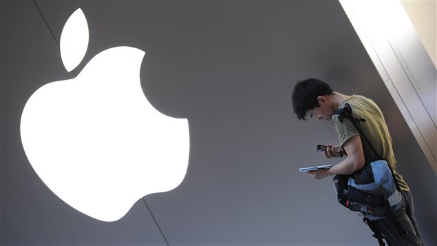 Un consommateur chinois consulte son iPad devant un logo Apple.