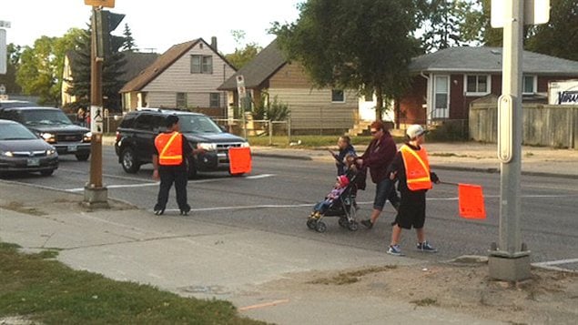 Des patrouilleurs de quartier aident les piétons à traverser la route jeudi près de l'École Archwood à Winnipeg.