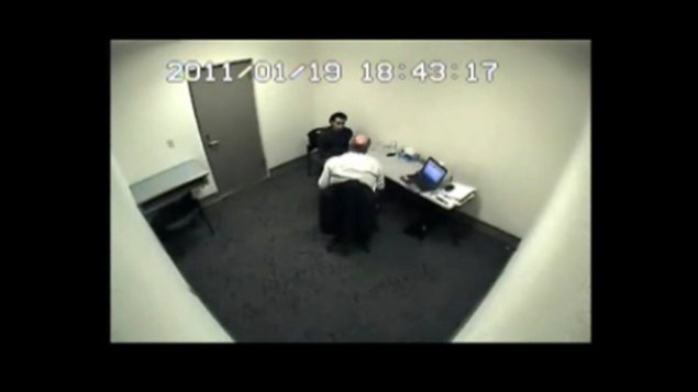 Un policier interroge le présumé terroriste Tahir Sharif