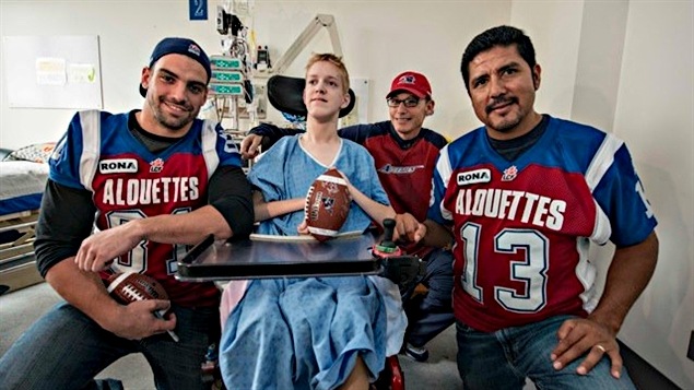 Patrick Lavoie, Marc Trestman et Anthony Calvillo entourent un enfant malade.