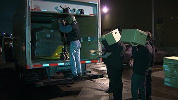 Des enquêteurs de Revenu Québec chargent des boîte de documents dans une camion.