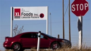 Une voiture roule devant un panneau de XL Foods