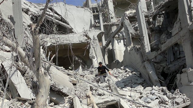 Un homme marche parmi les décombres à Arbeen en banlieue de Damas en Syrie.