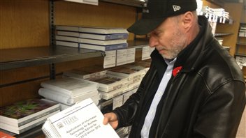 Murray Sang, directeur au SASS, explique que des dépliants sur l'aide disponible aux étudiants sont distribués lors de l'achat de manuels scolaires.