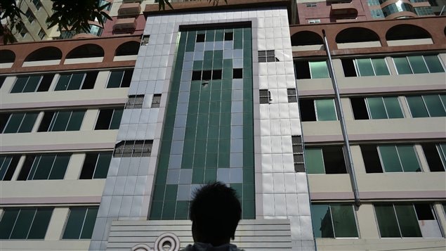 Un homme regarde la façade du plus grand immeuble de Mandalay, dont certains fenêtres sont tombées à la suite du séisme
