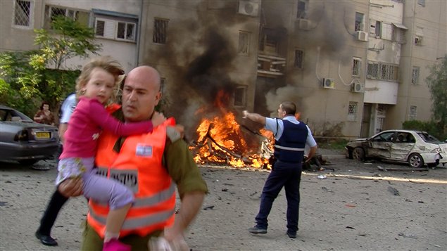 Un soldat israélien évacue une jeune fille d'un site touché par une roquette lancée depuis la bande de gaza dans le sud d'Israël.