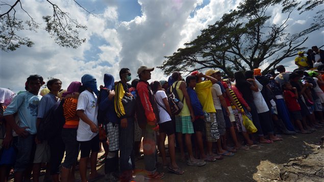 Des Philippins sinistrés après le passage du typhon faisaient la queue pour avoir de la nourriture, dimanche à New Bataan, dans le sud du pays.