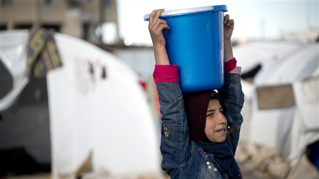 Une enfant transporte de l'eau dans un camp de réfugiés