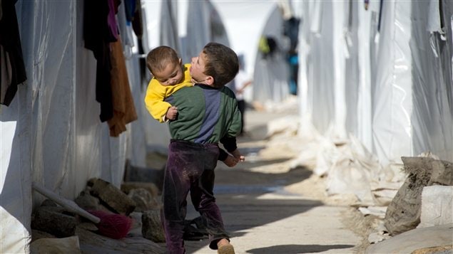 Un garçon prend son jeune frère pour le ramener à leur tente dans un camp de réfugiés situé à la frontière entre la Syrie et la Turquie.