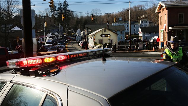 Des policiers montent la garde devant l'entrée de la rue qui mène à l'école Sandy Hook.