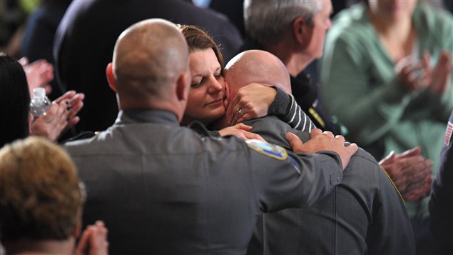 Une femme réconforte un membre du corps de police de Newtown quelques minutes avant que Barack Obama ne prononce son discours lors de la cérémonie religieuse.