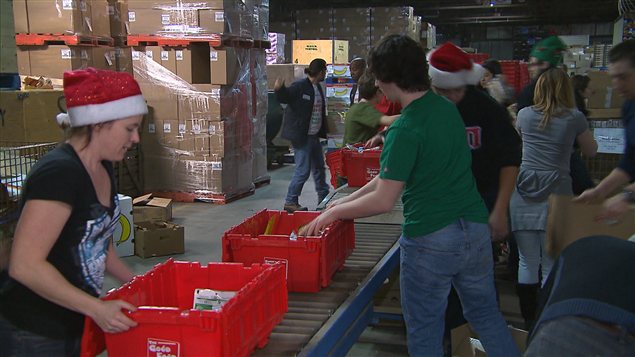 متطوعون يملأون سلال الأغذية في فترة الميلاد في "مواسون مونتريال" (Moisson Montréal)، أكبر بنك للأغذية في جزيرة مونتريال