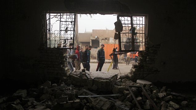 Des Irakiens observent les dommages subis par un édifice après un attentat survenu en novembre 2012, à Bagdad