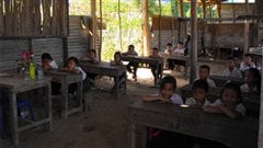 Des élèves de l'école élémentaire de Pakxoun, au Laos, sont assis dans leur bâtiment décrépi.