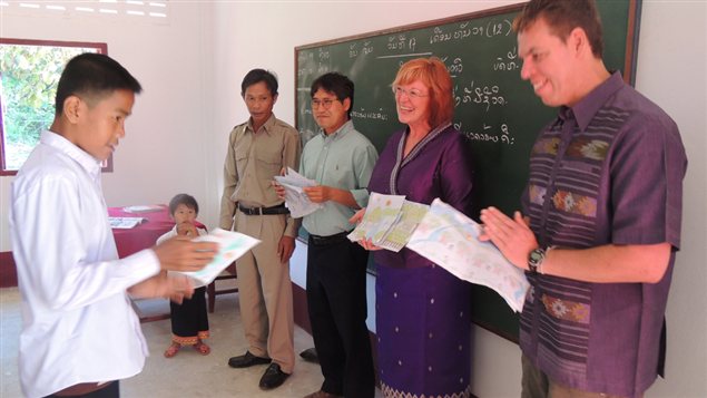 Un élève de cinquième année de l'école élémentaire de Ban Kava au Laos montre son dessin à François Tremblay (avant-plan gauche), Linda Lindsay et Ken Thongsay Phanlouvong, de School for Kids in Laos (SKL), le 17 décembre 2012.