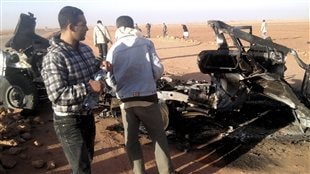 Des hommes examinent les restes d'un véhicule détruit près du site d'In Amenas, en Algérie.