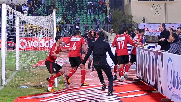 Des joueurs fuient le stade alors que les partisans commencent à s'affronter sur le terrain, le 1er février 2012