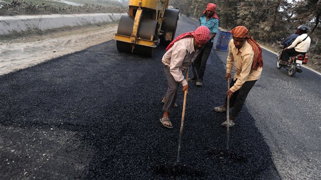 Des travailleurs indiens asphaltent une route.