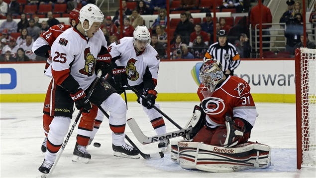 Dan Ellis des Hurricanes de la Caroline stoppe le tir de Chris Neil des Sénateurs d'Ottawa.