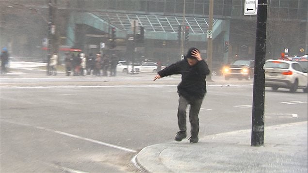 Une puissante bourrasque de vent malmène un piéton au centre-ville de Montréal.
