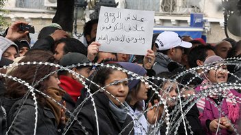 Des manifestantes chantent derrière un barbelé devant le ministère de l'Intérieur, à Tunis.