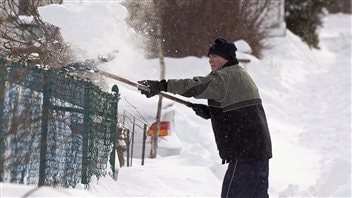 Un habitant de Dartmouth, en Nouvelle-Écosse, déneige devant sa résidence.