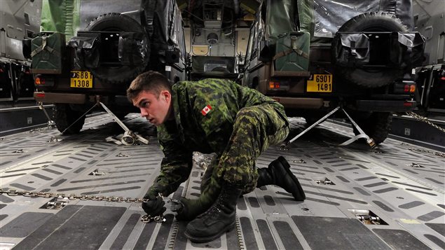 Un militaire canadien s’assure de bien immobiliser des jeeps français à l’intérieur de l’avion de transport CC-177 fourni par le Canada pour la mission au Mali.