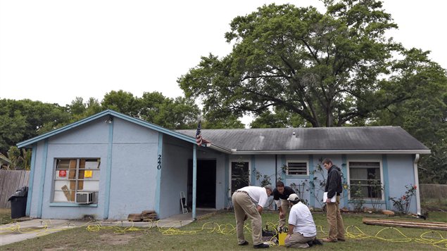 En Floride, des ingénieurs travaillent devant la maison au-dessous de laquelle s'est formé un gouffre qui a avalé un homme.