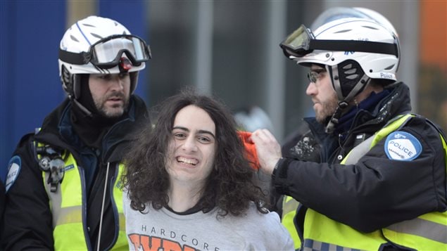 Un manifestant et deux policiers de la ville de Montréal lors de la manifestation annuelle contre la brutalité policière le 15 mars 2013.
