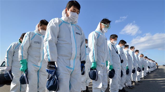 Des policiers, en tenue anti-radiations, proches de la centrale de Fukushima, le 11 mars 2013, à l'occasion du deuxième anniversaire du tremblement de terre.