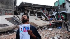 مواطن من دكا يحمل صورة أقرباء له قتلوا نتيجة تهدم ورشة نسيج 