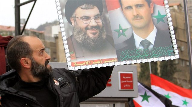 من الأرشيف: متظاهر في سوريا يرفع صورة تضم الرئيس السوري وأمين عام حزب الله