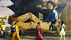 Des passants circulent devant un portrait g�ant de la superstar bollywoodienne Amitabh Bachchan, � Mumbai, en Inde / � Rafiq Maqbool, Presse canadienne