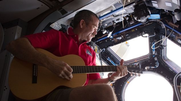 Chris Hadfield joue de la guitare dans la coupole d'observation de la SSI.