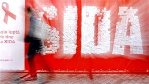 Un hombre camina frente a una pancarta que habla de la lucha contra el SIDA en Rumania.