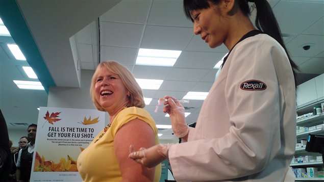 La ministre ontarienne de la Santé reçoit le vaccin contre la grippe dans une pharmacie Rexall en octobre 2013 